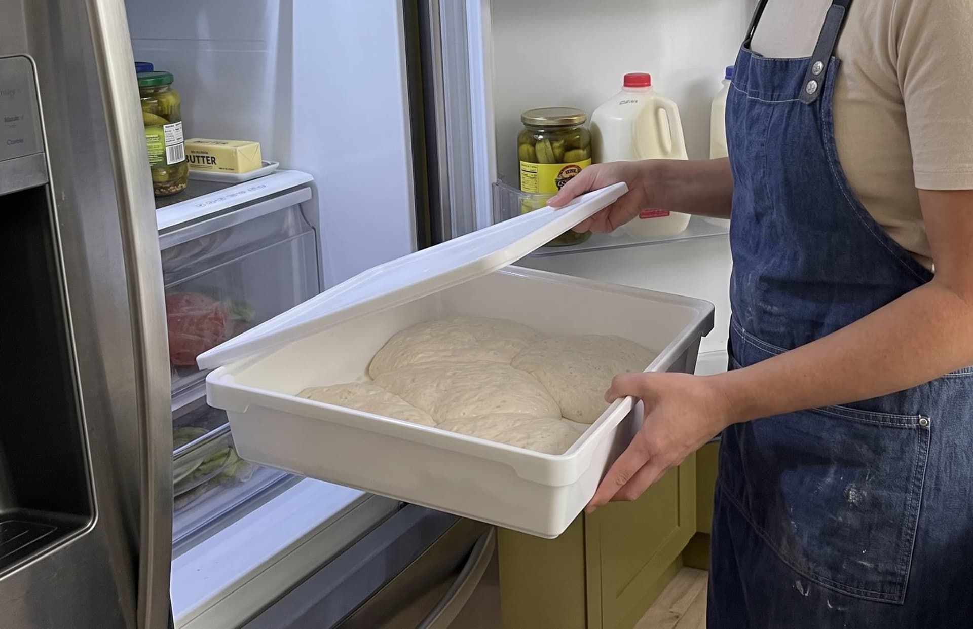 Egy ember éppen túlkelt tésztát vesz ki a hűtőszekrényből